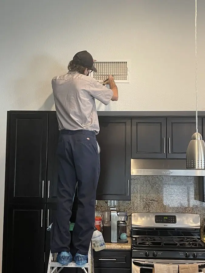 Technician inspecting an air vent during HVAC service in New York